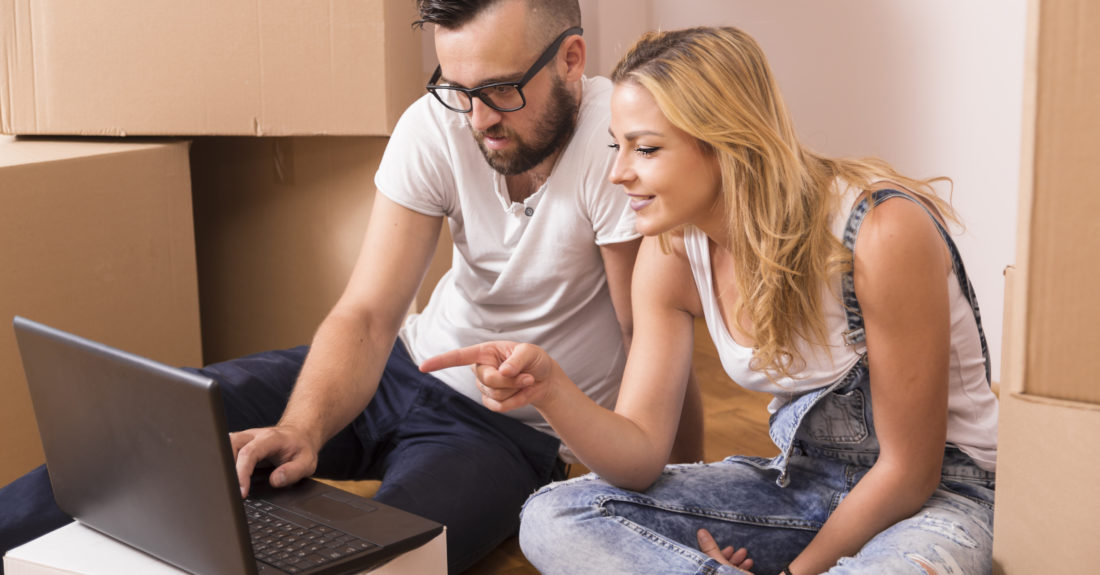 Young couple in love sitting on the floor of their new apartment, planning redecoration